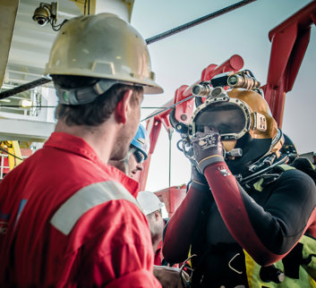 Two men, one in hard hat and one in a yellow diving helmet