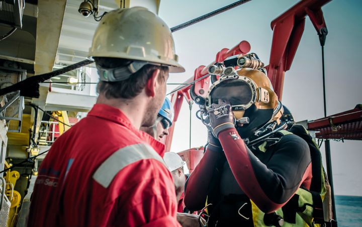 Two men, one in hard hat and one in a yellow diving helmet